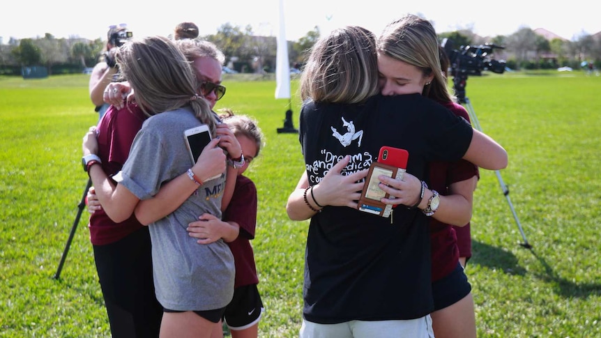 People embrace at the memorial outside Marjory Stoneman Douglas High School