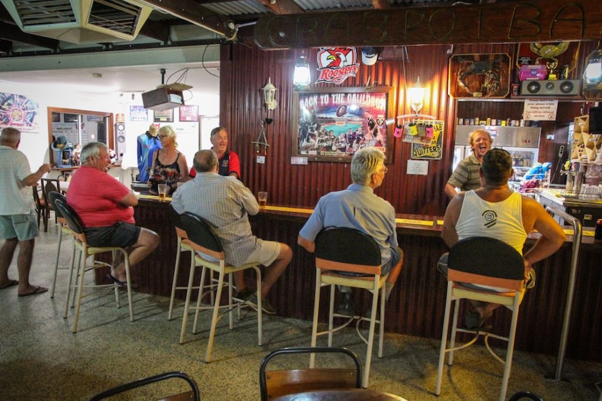 People sitting around on stools at a bar, smiling