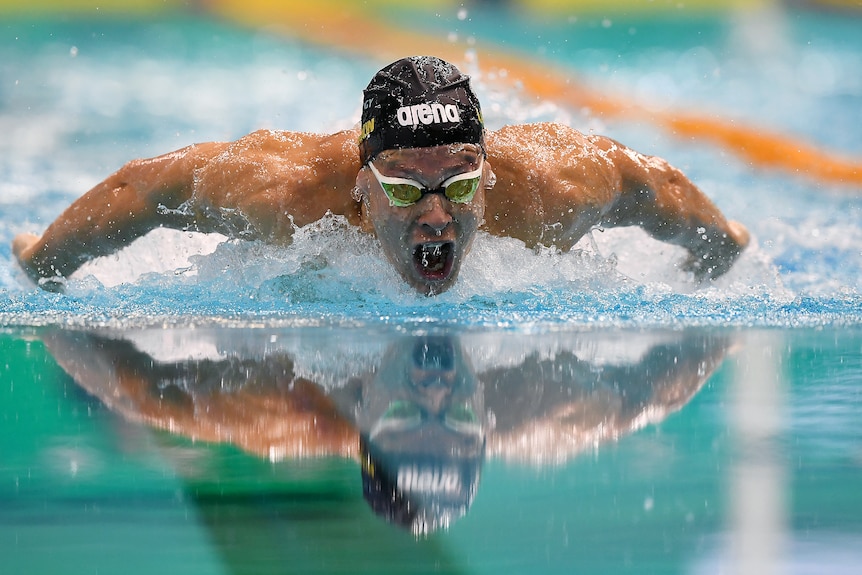 Man in black cap swims in pool