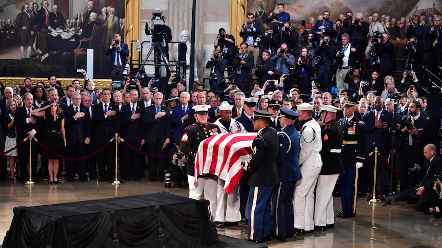 A military honour guard carries the casket of former Senator John McCain into the US Capitol Rotunda.
