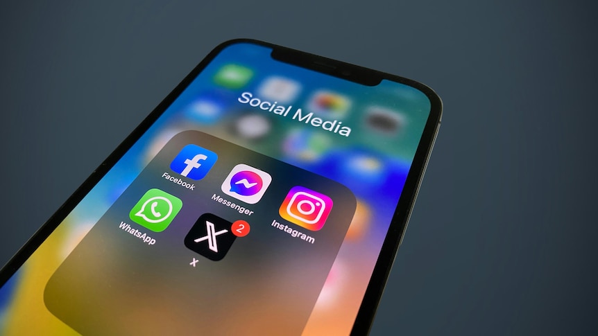 A smartphone displaying a folder of social media apps including Facebook, Instagram and X