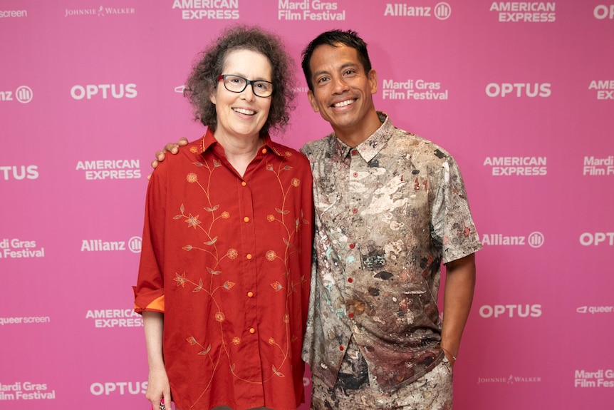 Molly Reynolds and Roberto Meza Mont pictured in front of a bright pink background at the Mardi Gras Film Festival.