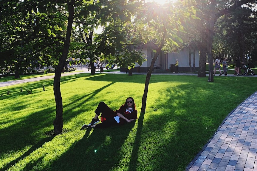 Zhenya Gavra lies on the grass outside the Mariupol Drama Theatre in 2018.