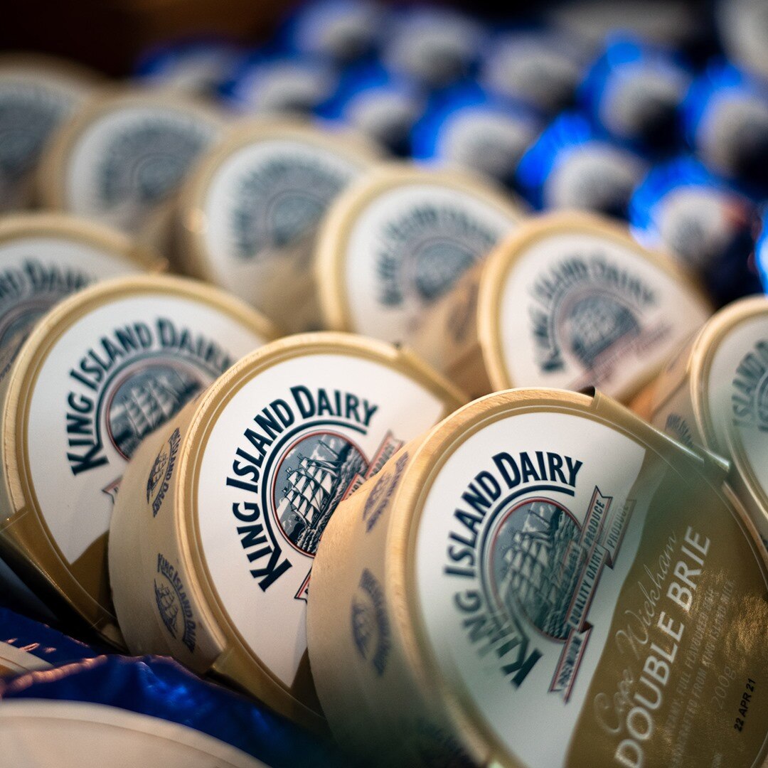 A dozen King Island Dairy double brie cheese wheels splayed with their labels showing.