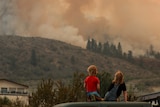 Locals watch as a fires come over the hill