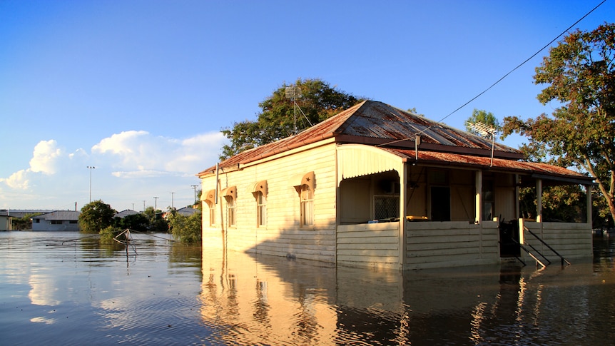 A house partially underwater, with a rotary clothesline mostly submerged beside it.
