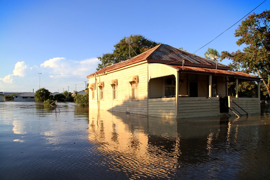 A house partially underwater, with a rotary clothesline mostly submerged beside it.