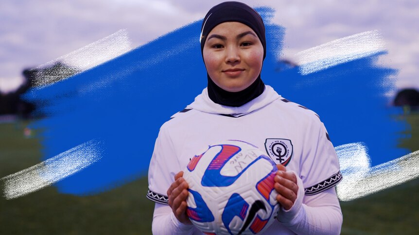 Adiba smiles to camera on the soccer field in her soccer uniform while holding a soccer ball.