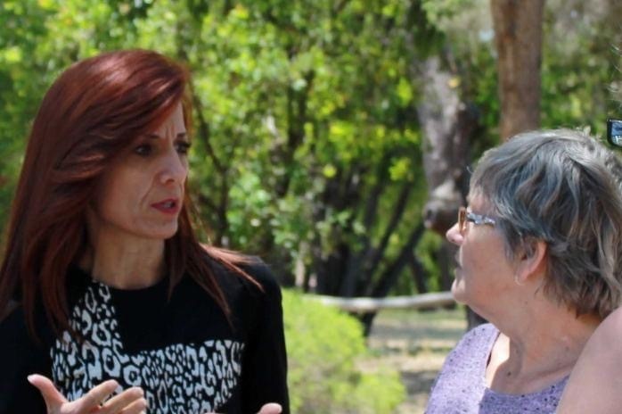 Upper House South West MP Adele Farina is talking constituents outside, greenery is in the background