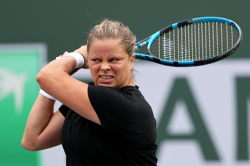 Kim Clijsters hits a shot and grimaces with her racquet behind her head