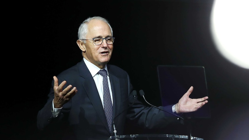 Malcolm Turnbull with his arms outstretched delivering a speech at a lectern.