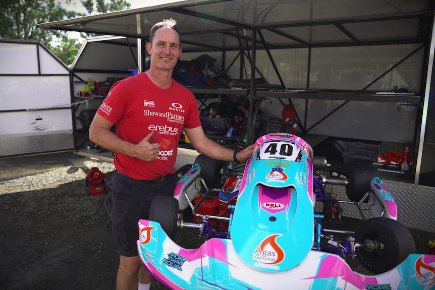 Adrian Flack stands next to a go kart while giving a thumbs up to the camera.