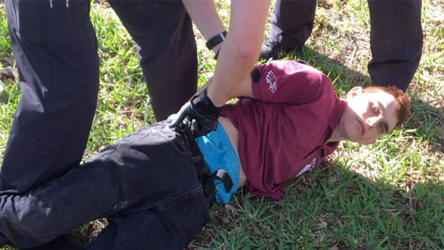 Picture of a man on the ground with his hands being handcuffed behind his back and being arrested by police