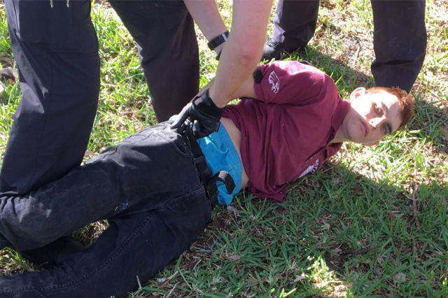 Picture of a man on the ground with his hands being handcuffed behind his back and being arrested by police
