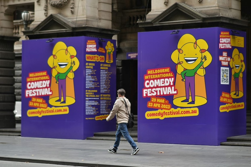 A person walks past promotional signage for the Melbourne International Comedy Festival.