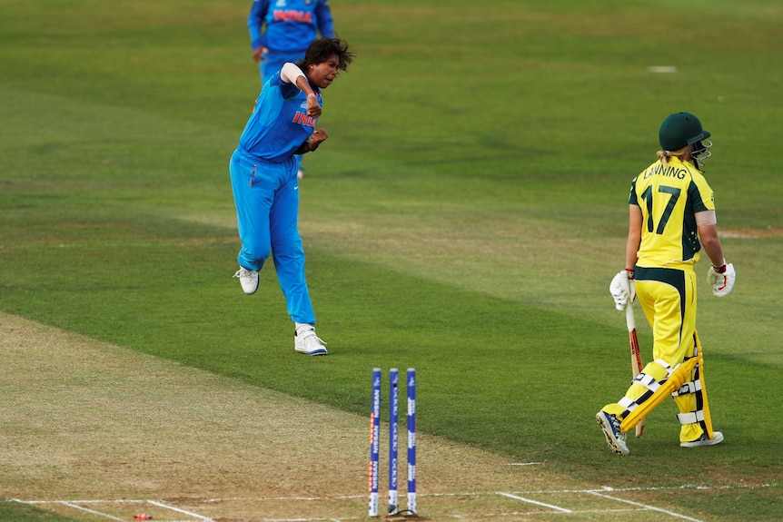 A bowler leaps, punching the air in triumph as a batter walks off after being dismissed.