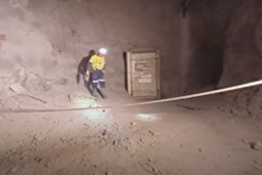 A worker in high-viz and hardhat in a well-lit underground cavern. 
