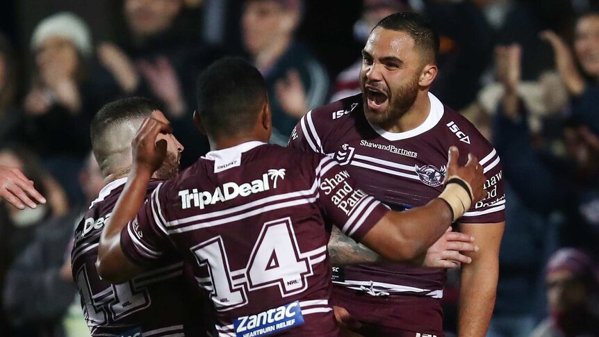 An NRL player shouts with joy as he celebrates a try with his teammates.