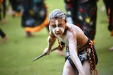 A bare chested Indigenous boy wearing face paint performs in a corroboree.