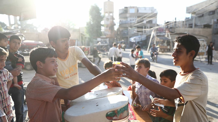A Syrian boy serves a juice on the third day of the Al-Adha Eid