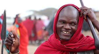 Tanzanian man wearing a red and black scarf stands in a market place