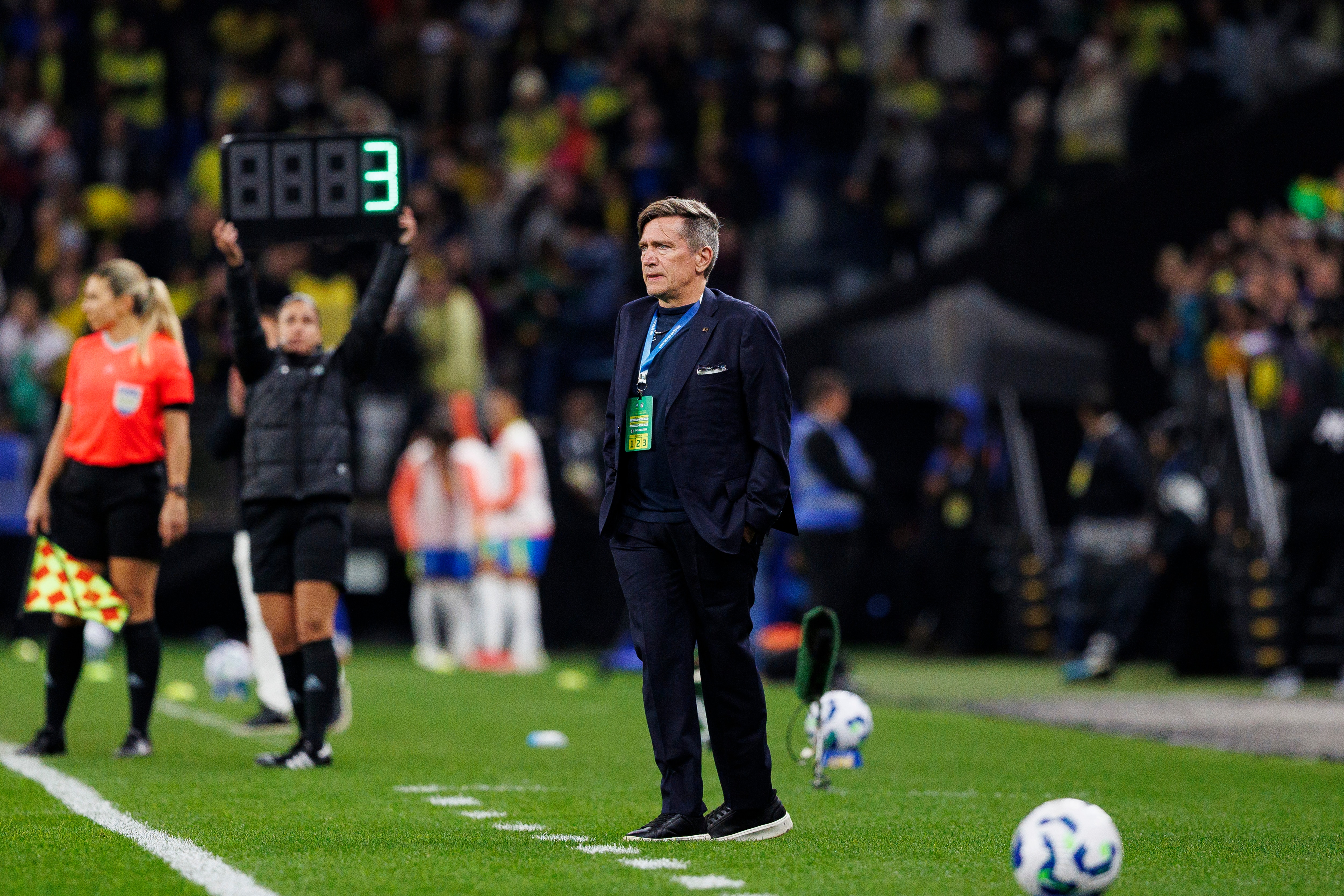 Um homem mais velho está ao lado de um campo de futebol.