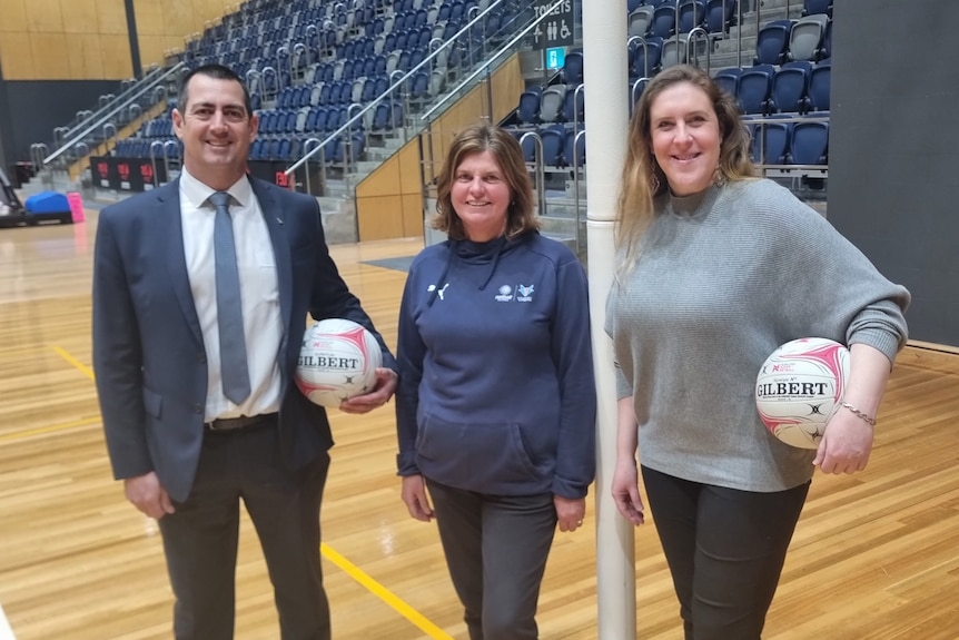 Three Netball executives, with two holding netballs. From left Andrew Cooney, Carol Cathcart, and Teigan Redwood.