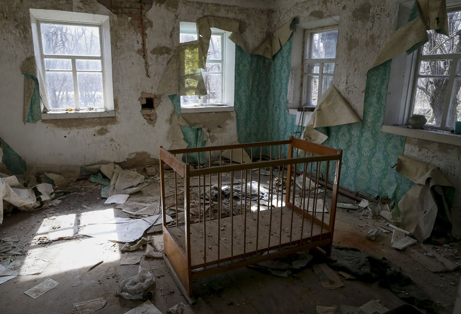 A baby cot sits inside a house in an abandoned village near the Chernobyl nuclear power plant.