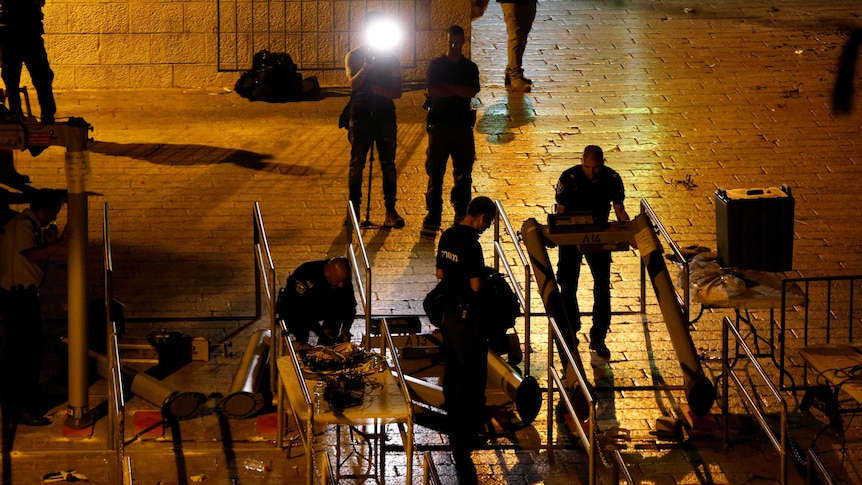 Israeli security forces remove metal detectors with lights at night.