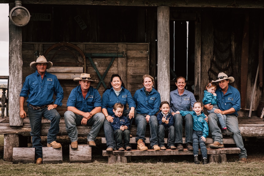 A group of farmers sitting outside an old farmhouse