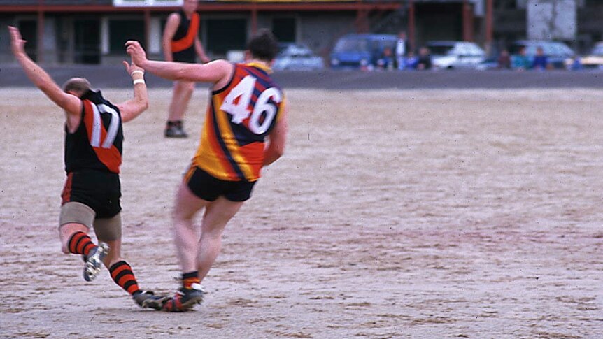Footballers play on Queenstown's gravel oval in Tasmania's west.