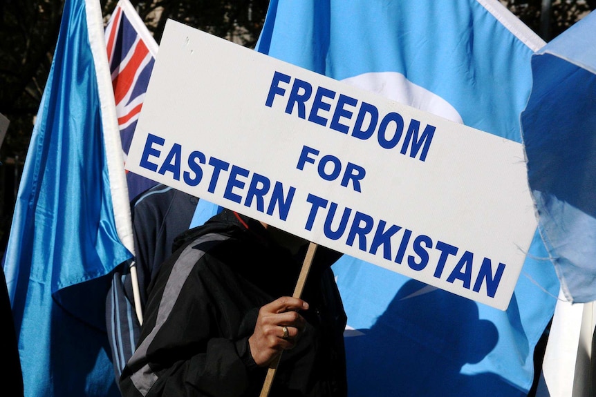 A protester attends an anti-Beijing rally with a placard reading "Freedom for Eastern Turkistan".
