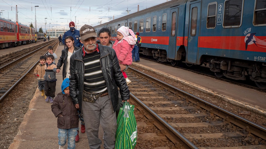 Refugees fleeing the war in Ukraine walk on a platform after disembarking from a train