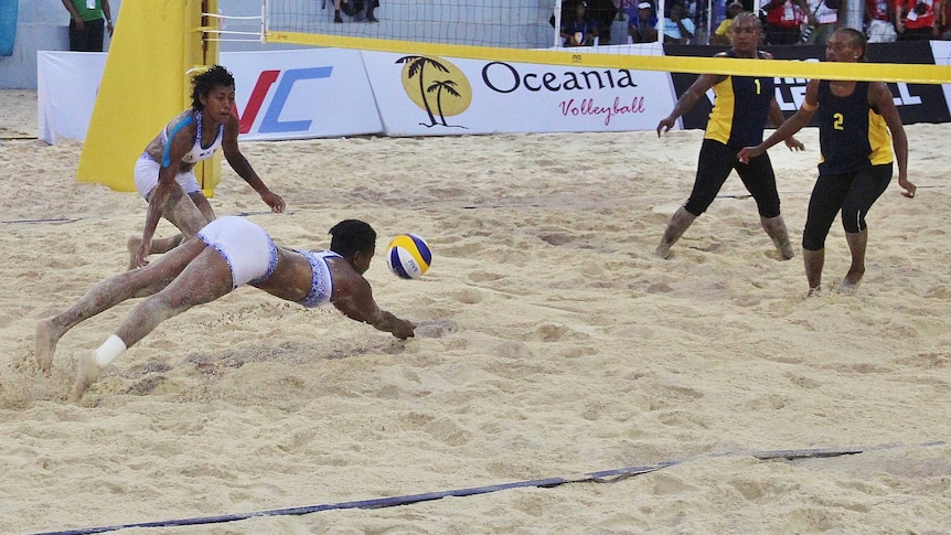 One Fijian player watches as her teammate dives towards the net trying to keep the ball in the air.