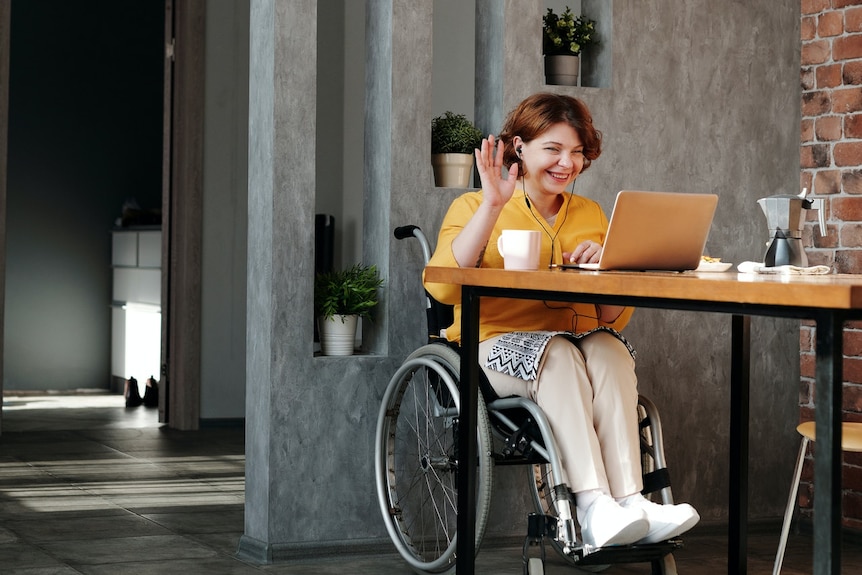 A woman in a wheelchair uses her laptop computer