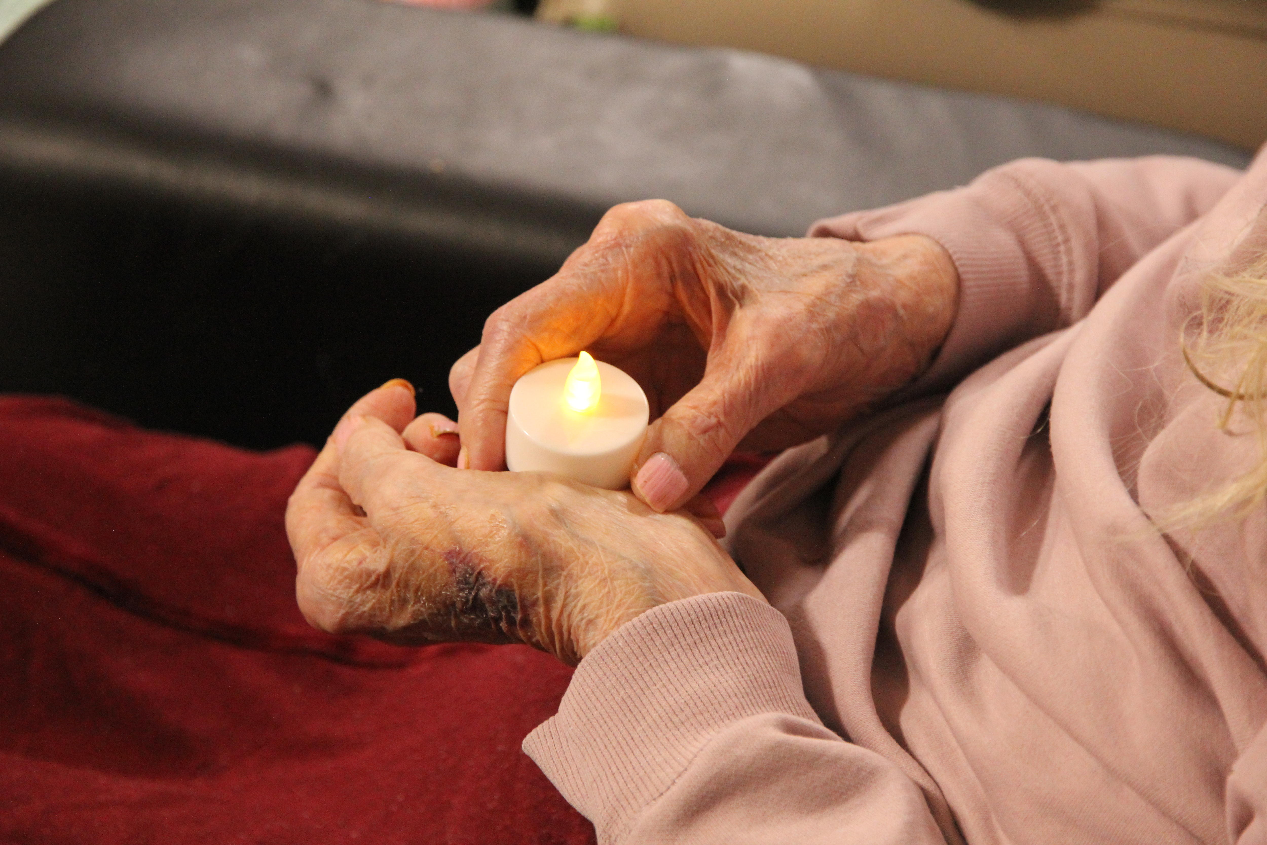 Las manos de una persona mayor sostienen una vela.