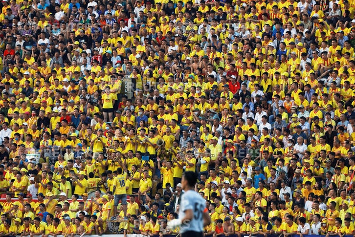 Thousands of fans pictured watching the soccer match, wearing yellow shirts and team colours.