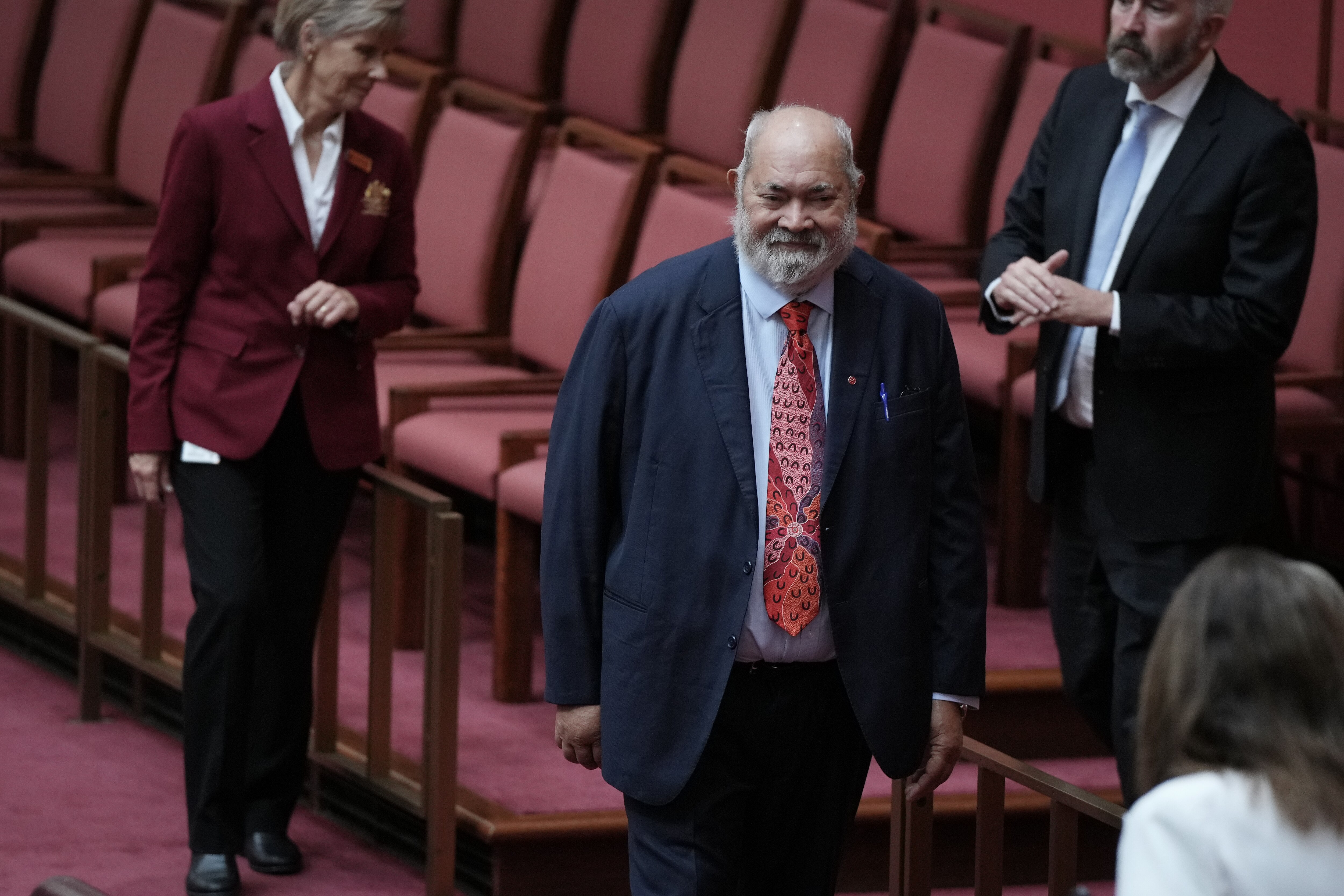 Dodson, with short beard, walks along a row of senate seats.