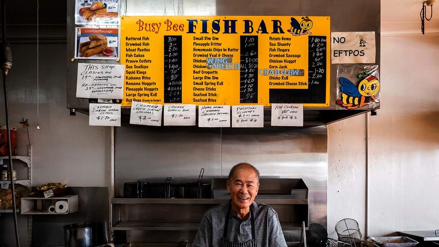 Kent Wong stands in front of the menu and deep fryer at his Bush Bee Fish Bar in Bundaberg./