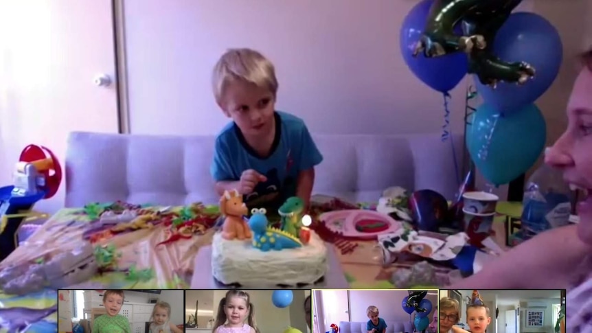 Young boy in front of a birthday cake, balloons to the side and the bottom of the photo has other children in screen boxes.