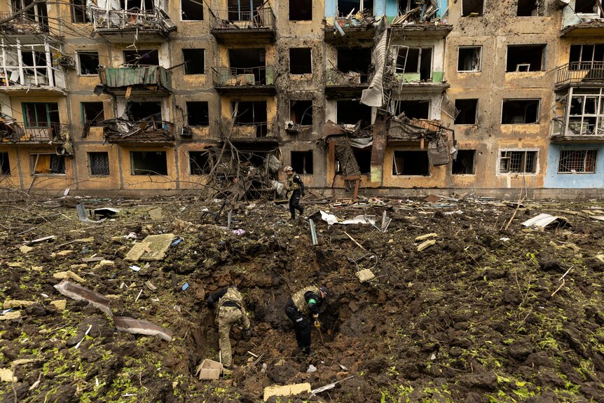 Soldiers inspect missile strike aftermath hole in the ground.