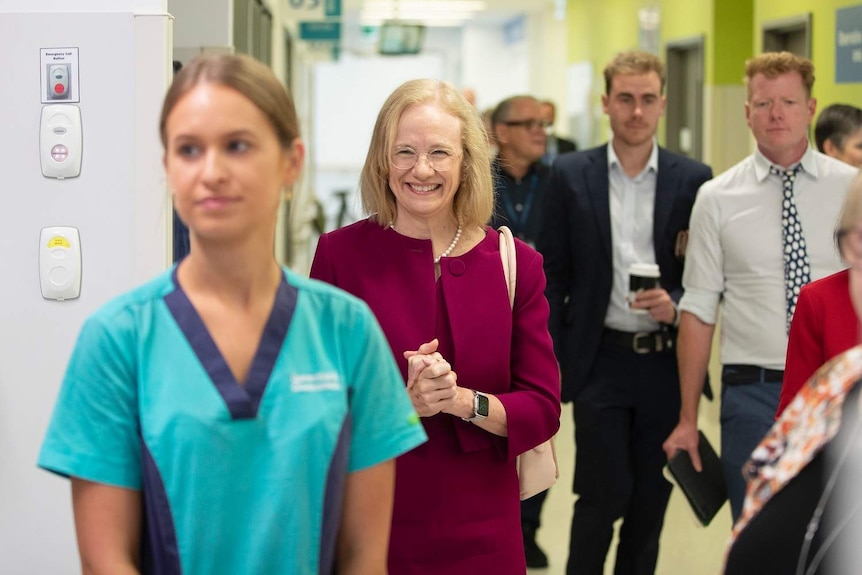 Dr Jeannette Young stands smiling as she walks through Gold Coast University Hospital.