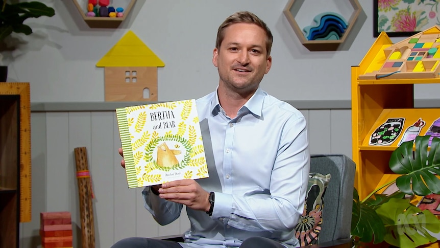 Teacher Matthew Price holds up story book, Bertha and Bear