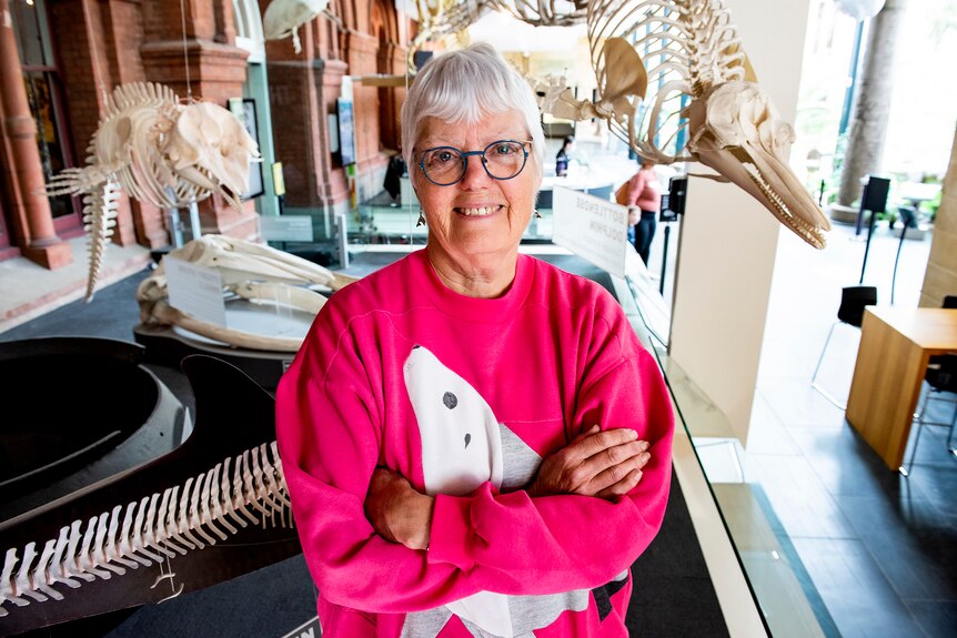 A woman stands beneath bone specimens of animals in a museum foyer