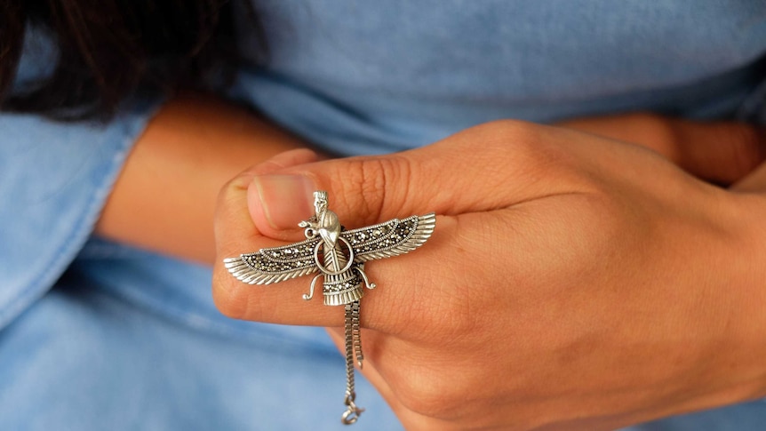 Close up of Auzita holding silver Zoroastrian pendant.
