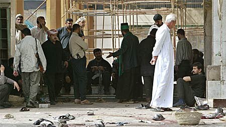 Iraqi Shiite men sit near the site of an explosion inside a Baghdad mosque.