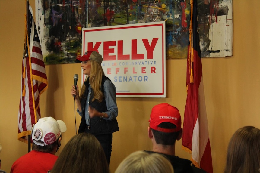 Senator Kelly Loeffler speaks into a microphone in front of an audience.