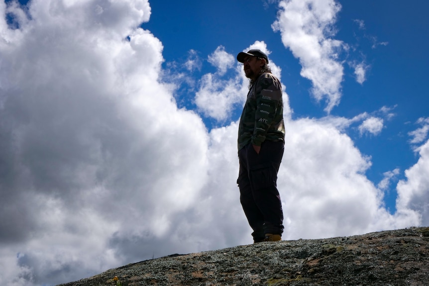 A man stands on top of a cliff edge