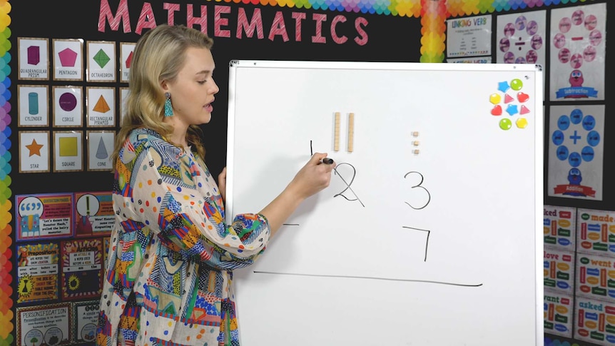 Female teacher crosses out number on whiteboard