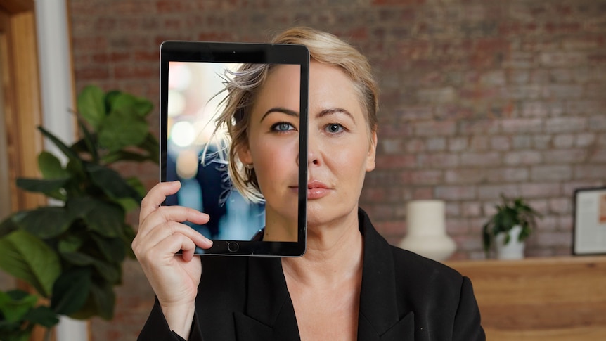 Blonde woman holds eye iPad to her face. The iPad screen shows the covered side of her face as a glam photograph